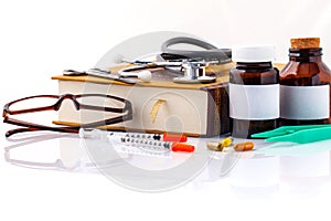 Stethoscope on a textbooks and bottle of pills isolated on white