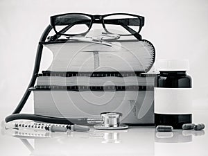 Stethoscope on a textbooks and bottle of pills isolated on white