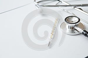 Stethoscope, Thermometer, Document Board, Notebook, Pen  on white background and copy space