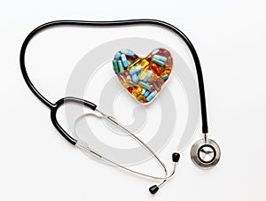 Stethoscope on white background with pills in shape of heart