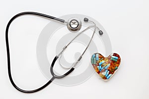 Stethoscope on white background with pills in shape of heart