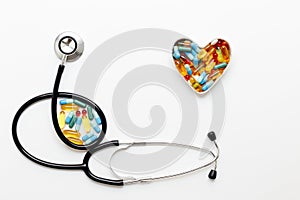 Stethoscope on white background with pills in shape of heart