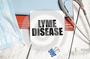 Stethoscope and white card with lyme disease text on notebook.