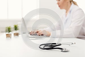 Stethoscope on white desk, selective focus