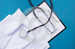 Stethoscope, white uniform of doctors folded and lies on the table