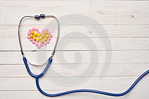 stethoscope on wooden background pills vitamins Pharmaceuticals