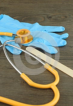 Stethoscope, wooden tongue depressor and glove