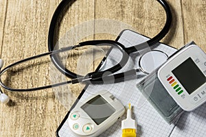 Stethoskope on wooden desk with blood pressure measurement