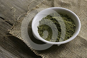 Stevia powder in white plate on rug sack on wooden background