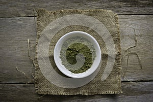 Stevia powder in white plate on rug sack on wooden background