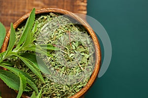 Stevia rebaudiana.Stevia dietary sweetener. Fresh and dried crushed stevia leaves in a round cup on a green background