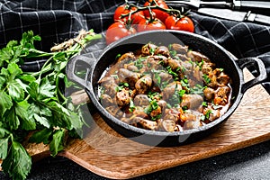 Stew with chicken hearts and vegetables with fresh parsley. Black background. Top view