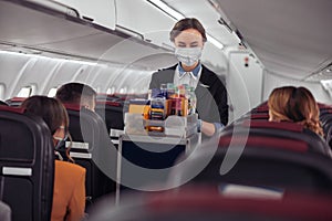 Stewardess carrying food trolley in airplane cabin
