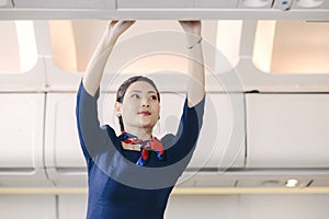 The stewardess helps the passengers to put their luggage in the cabin of the plane. Stewardess in the airplane