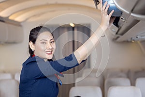 The stewardess helps the passengers to put their luggage in the cabin of the plane. Stewardess in the airplane