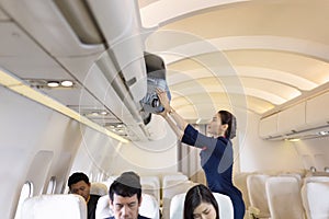 The stewardess helps the passengers to put their luggage in the cabin of the plane. Stewardess in the airplane