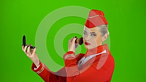 Stewardess looks in the mirror and paints her face with a tassel. Green screen