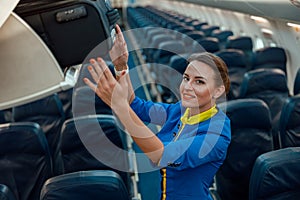 Stewardess putting travel bag in overhead luggage shelf in airplane