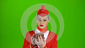 Stewardess in the red attire looks into the phone and is surprised. Green Screen