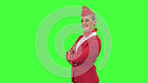 Stewardess in a red suit winks a slight flirt. Green screen. Side view