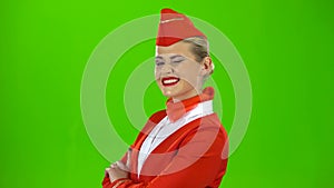 Stewardess in a red suit winks a slight flirt. Green screen. Side view