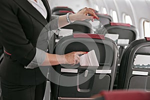 Stewardess shove napkin in seat of airplane jet photo