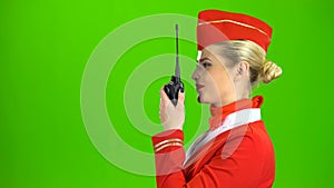 Stewardess speaks on the walkie talkie. Green screen. Side view