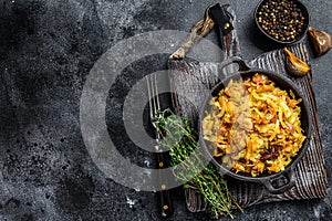 Stewed cabbage Bigos with mushrooms and sausages. Black background. Top view. Copy space