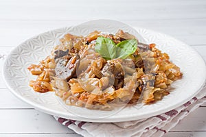 Stewed cabbage with mushrooms on white wooden background