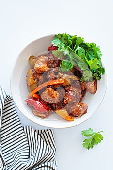 Stewed chicken fillet pieces with vegetables in white bowl with cilantro