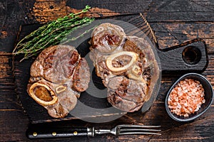 Stewed meat on the bone Osso Buco beef shank, italian ossobuco steak. Dark wooden background. Top view