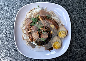 Stewed pork leg with Eggs on rice in white dish, delicious of  Thai food