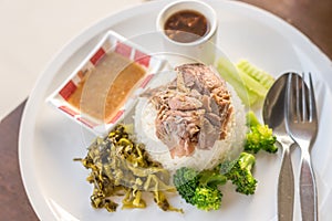 Stewed pork leg on rice on wooden table, asian food.