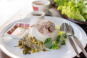 Stewed pork leg on rice on wooden table, asian food.