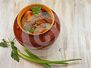 Stewed rabbit with vegetables Goulash in Copper Pot on shabby Wooden background, roasted beef meat with carrot, leek, onion in rou