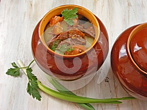 Stewed rabbit with vegetables Goulash in Copper Pot on Wooden Surface, roasted beef meat with carrot, leek, onion in round ceramic