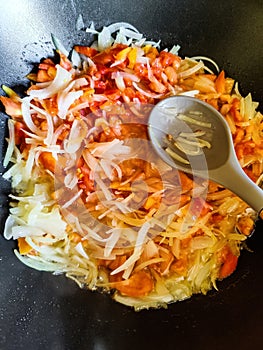 Stewed vegetables and silicone spatula with wooden handle in frying pan. Mixed Ingredients leek, carrot, bell pepper.