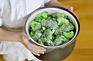 Stewpan with frozen broccoli in hands