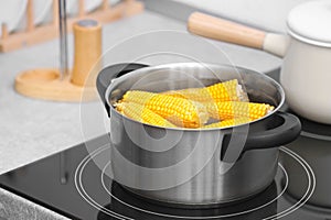 Stewpot with water and corn cobs on stove