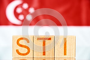 Sti index singapore. wooden blocks with sti lettering on singapore flag background.