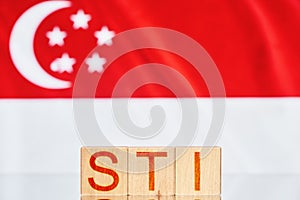 sti. wooden blocks with sti Straits Times Singapore in front of the Singapore flag.