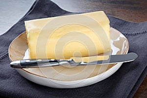 A stick of fresh butter with a knife on a plate