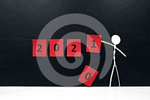 Stick man figure changing 2020 year red cubes to 2021 in black background with copy space. New Year celebration concept.