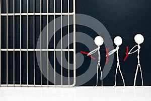 Stick man figure handcuffed tied with red rope going to a jail prison in dark background. Hostage, political prisoner, human right