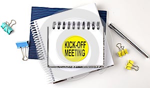 Sticker with KICK OFF MEETING text on notebooks on white background