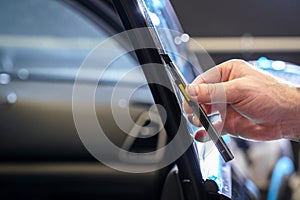 Sticker of a protective film on the headlight of a car in a car detailing studio