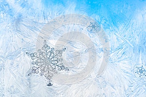 Sticker snowflakes on ice frosted window glass with blue sky seen in the background