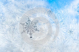 Sticker snowflakes on ice frosted window glass with blue sky seen in the background