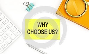 Sticker with the text WHY CHOOSE US on white background, near calculator and notebook