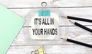 Stickers with pencils and notebook with text It`s all in your hands on wooden background